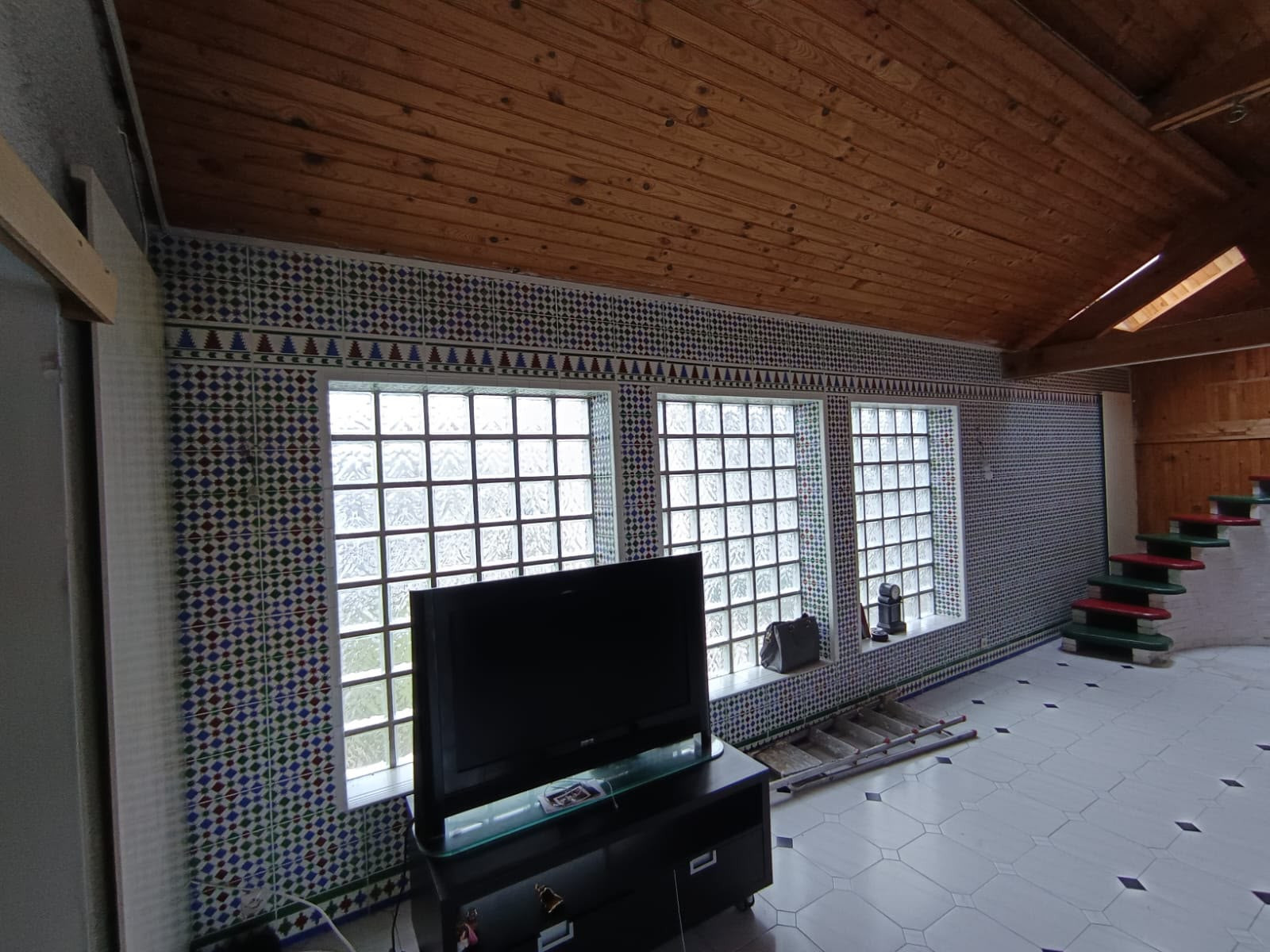 Avant travaux : pièce aux murs en azulejos, baies en pavés de verre et plafond en lambris