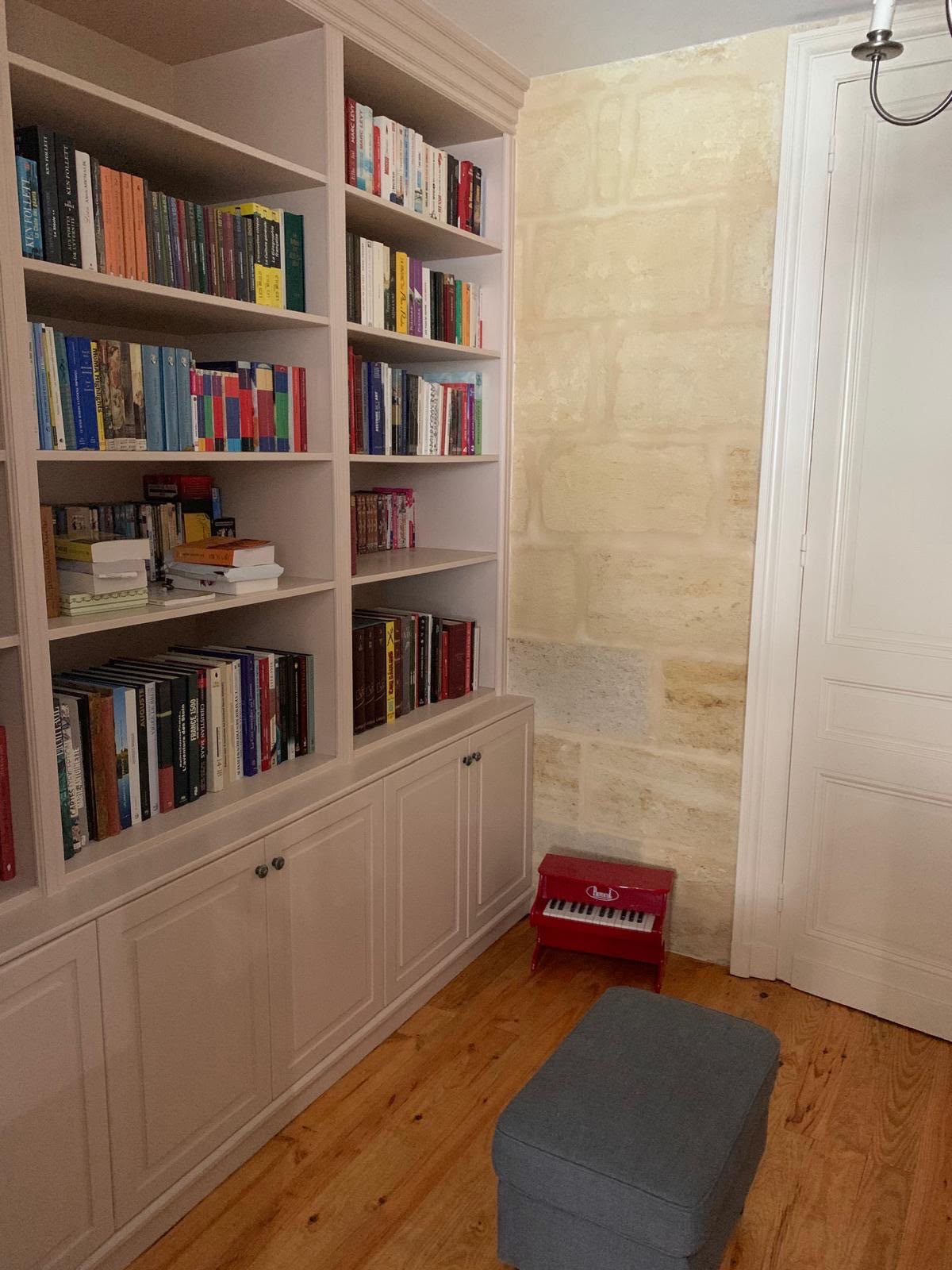 Bibliothèque toute hauteur contre mur en pierre · chantier des équipes partenaires