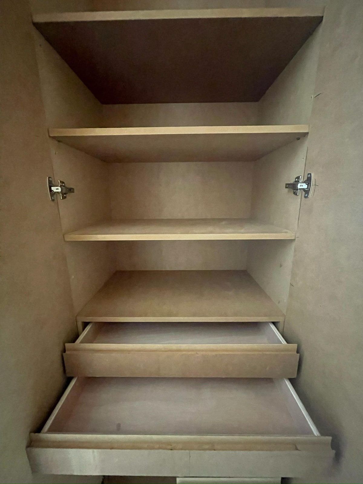 Intérieur d'un caisson sur mesure en panneau brut, tablettes et tiroirs sortis, charnières apparentes : les références de quincaillerie se relèvent à ce moment-là, pas trois ans plus tard. Chantier réel des équipes partenaires.