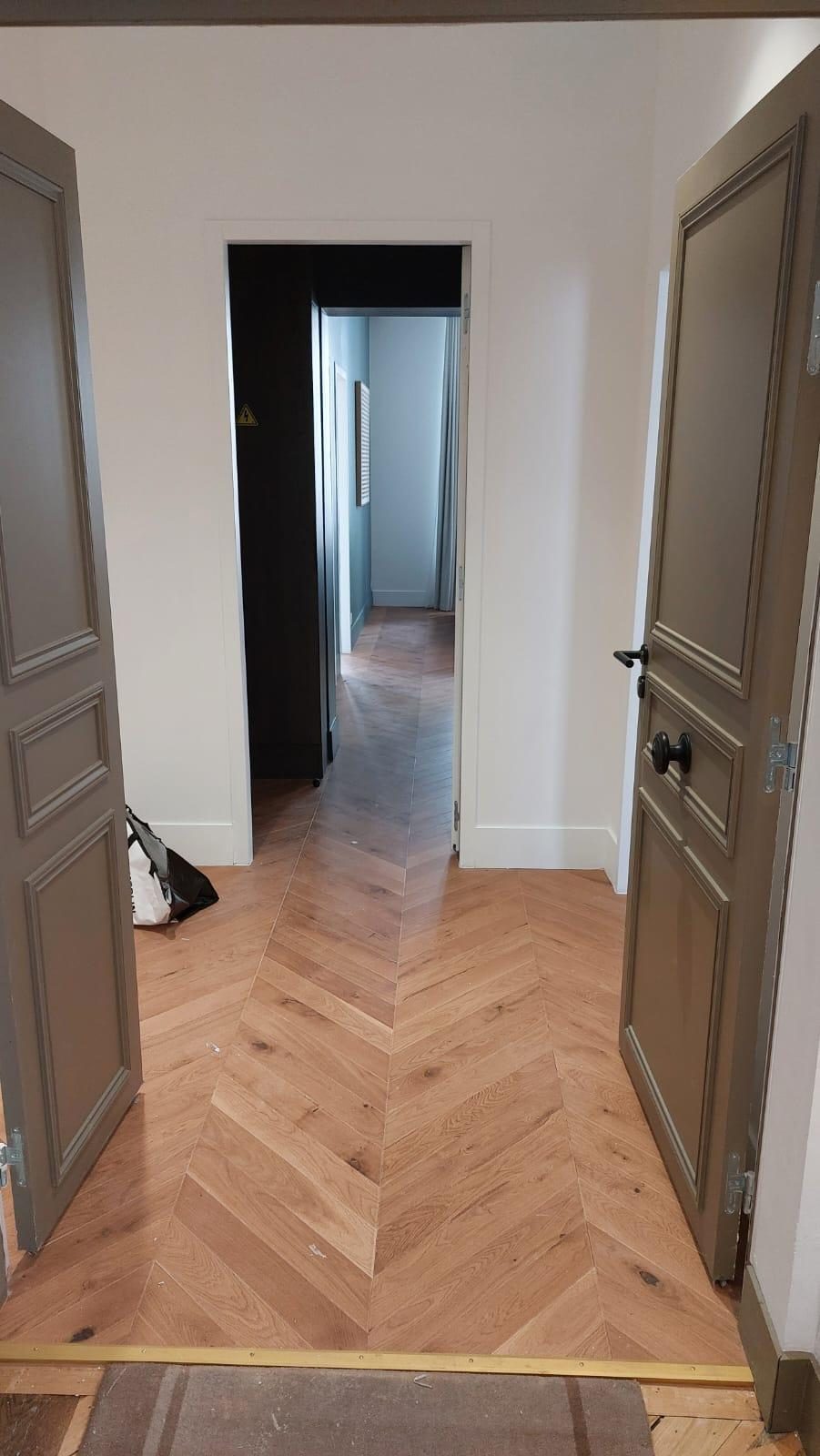 Dernier lot en place : parquet posé à chevrons et portes peintes, une fois les murs, les réseaux et les enduits terminés. Chantier réel des équipes partenaires.