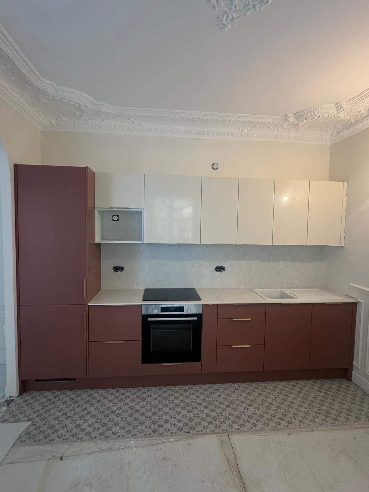 Cuisine terracotta et blanc sous corniches d'époque · chantier des équipes partenaires