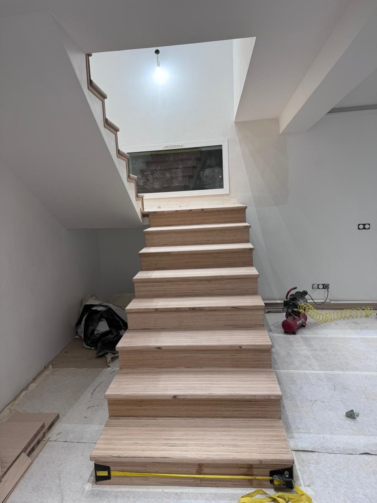 Escalier en cours de finition : marches et contremarches en contreplaqué à chant apparent, portées par un limon maçonné. Chantier réel des équipes partenaires.