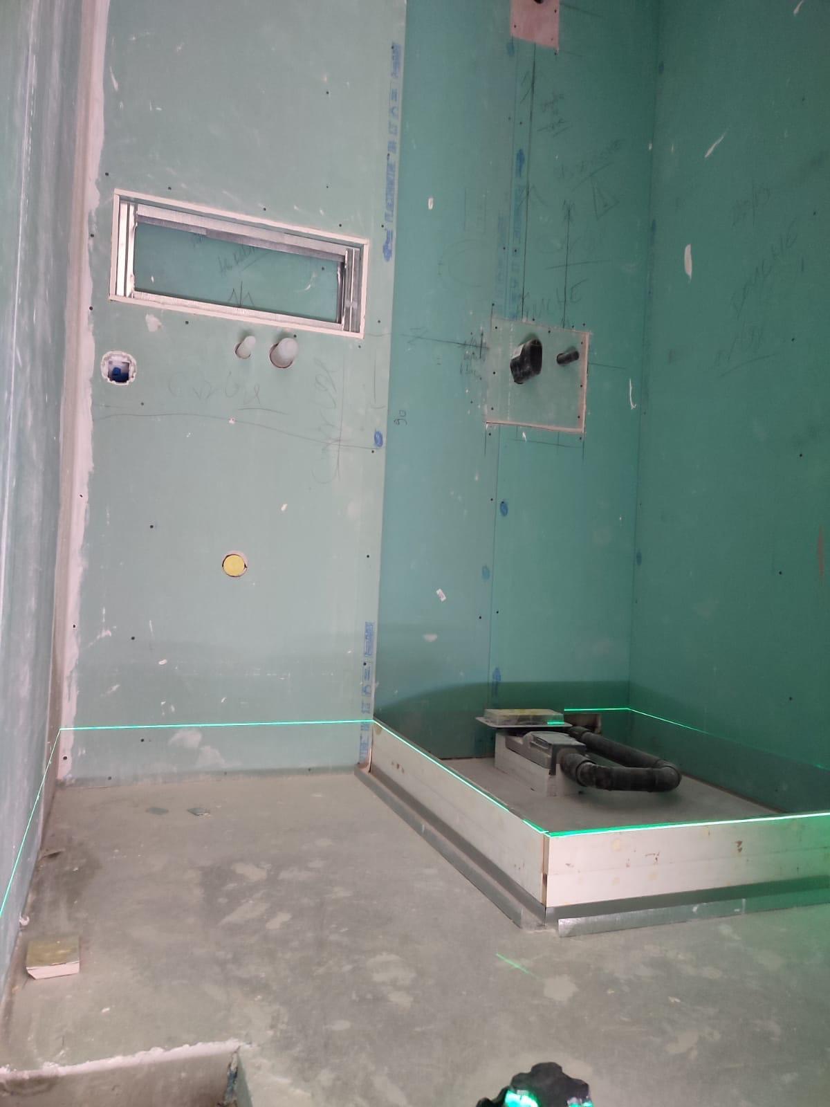 Implantation d'un receveur de douche au laser de niveau, plaques hydrofuges et réservations du mitigeur et de la bonde tracées à la main