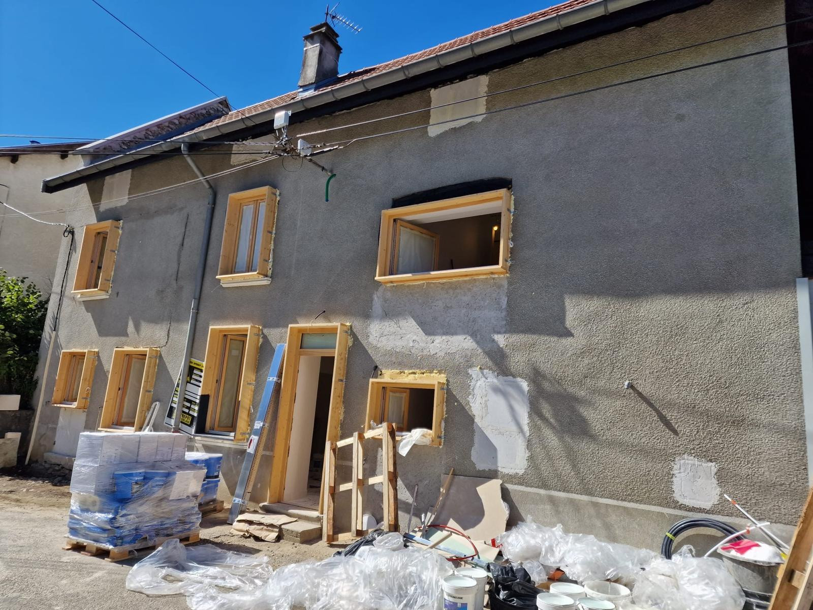 Avant ravalement : façade de maison de village en enduit tyrolien, rebouchages autour des menuiseries