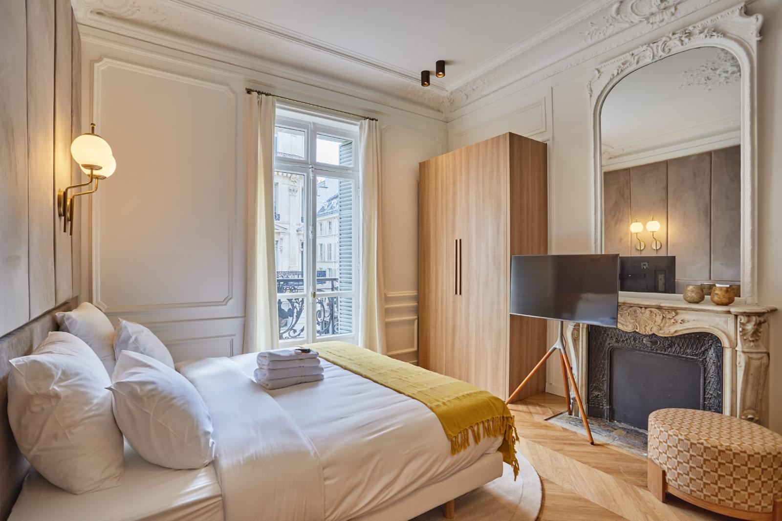 Chambre d'un appartement ancien rénové : cheminée de marbre et trumeau cintré d'origine conservés, dressing en placage bois clair