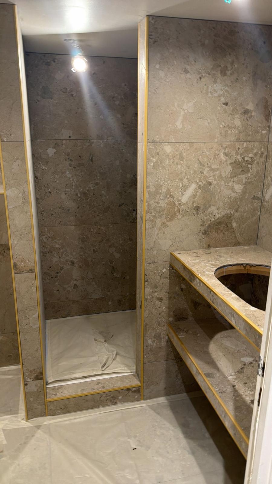 Douche en pierre grand format, chantier encore en cours, film de protection au sol : une fois la pierre posée, l'ouvrage d'étanchéité placé dessous n'est plus ni visible ni contrôlable. Chantier réel des équipes partenaires.