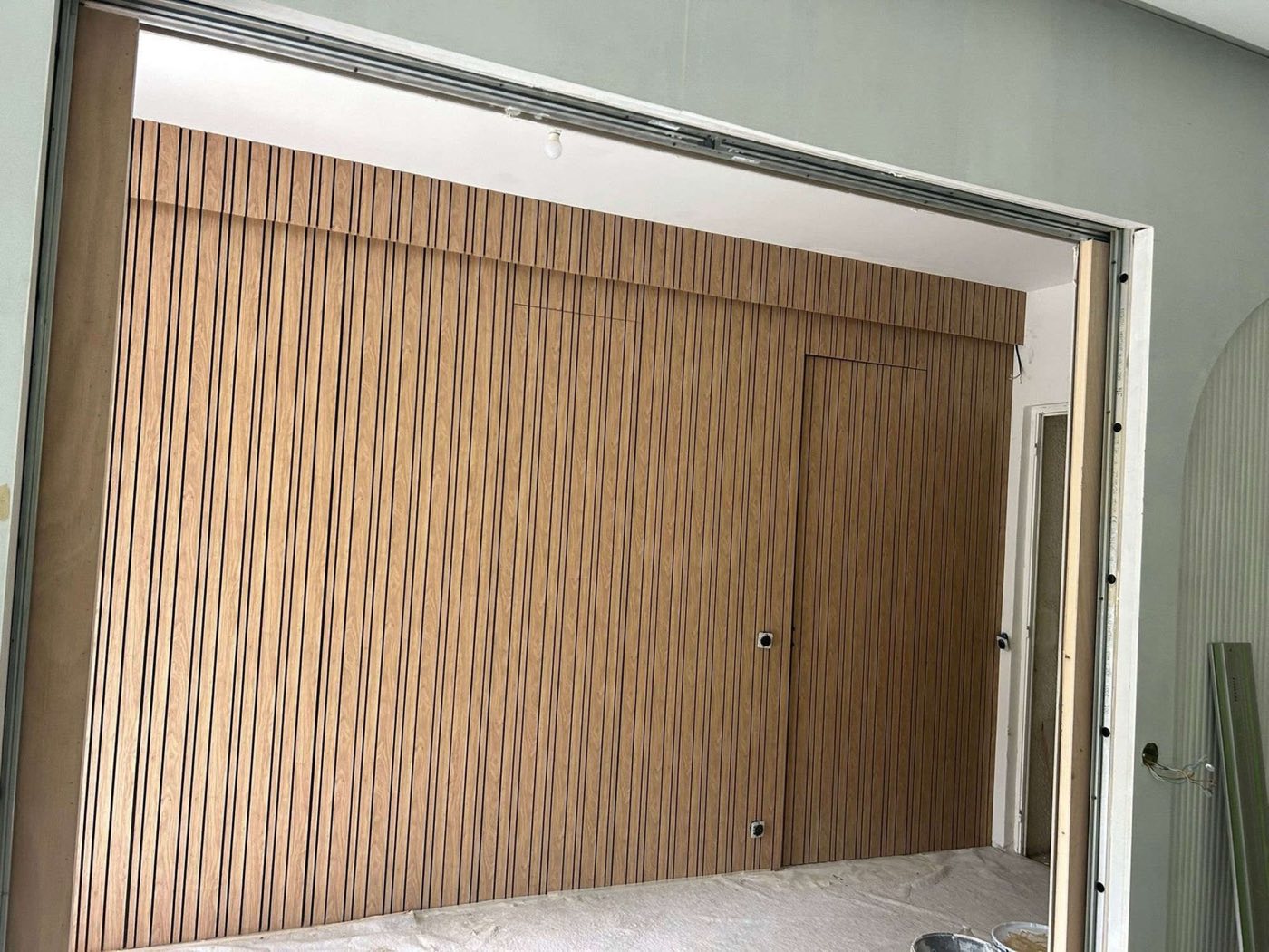 Mur de tasseaux et porte intégrée, en pose · chantier des équipes partenaires