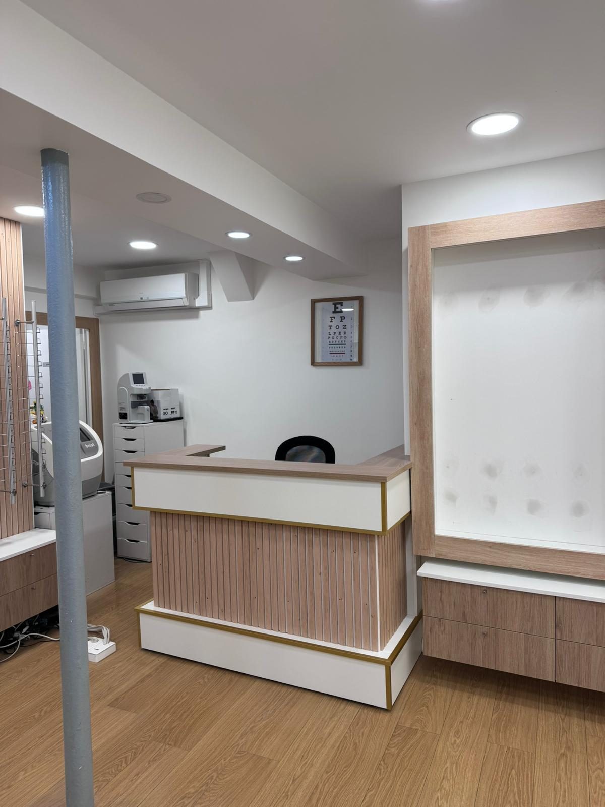 Local commercial livré : comptoir d'accueil habillé de bois et de laque, présentoirs muraux