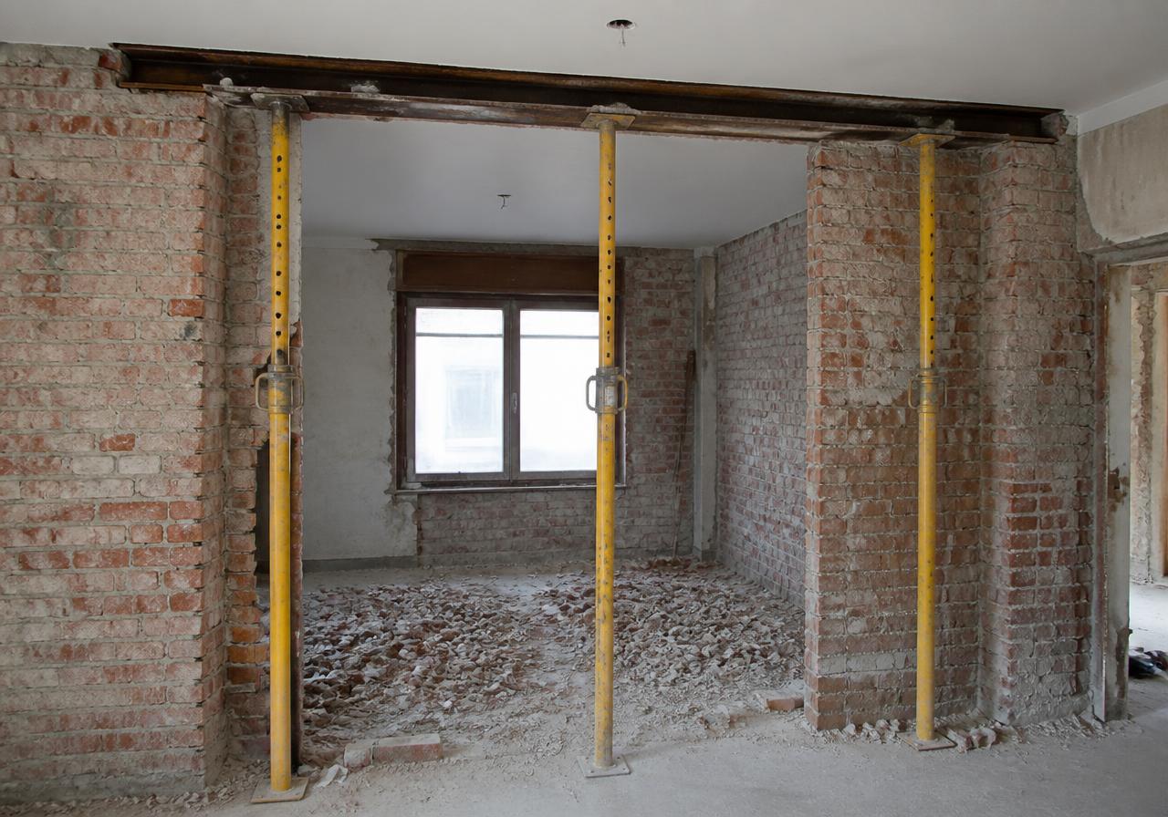 Ouverture pratiquée dans un mur en briques, trois étais métalliques réglables en appui sous la poutre posée en tête d'ouverture