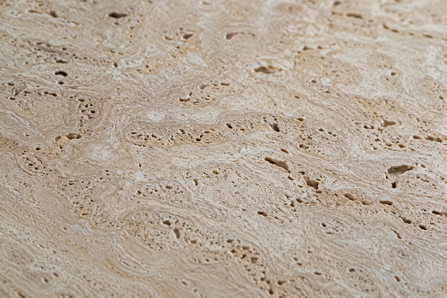 Gros plan sur la texture du travertin naturel, alvéoles et veinage caractéristiques