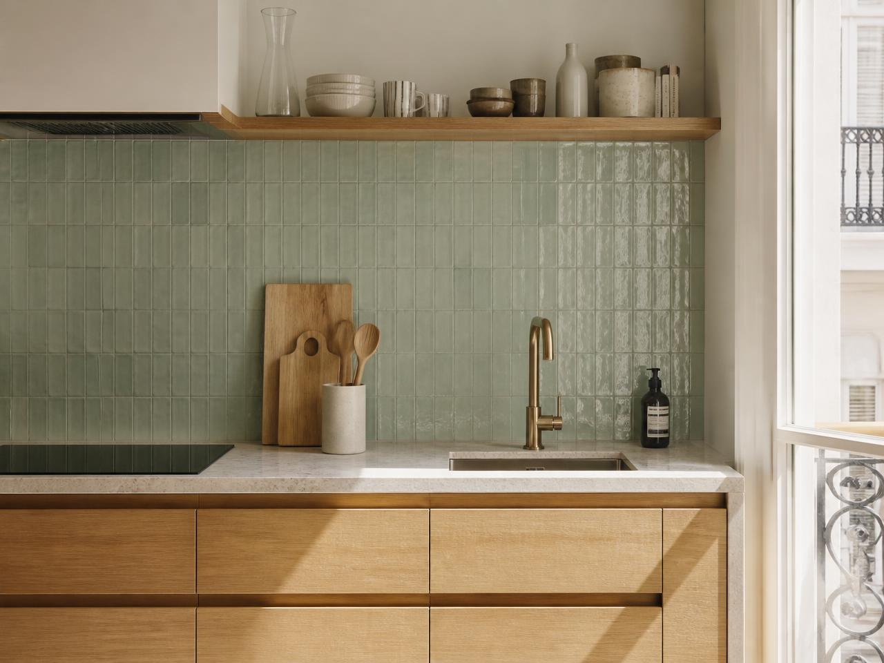 Crédence de cuisine en carreaux émaillés vert d'eau à surface ondulée, posés verticalement, plan de travail en pierre claire et façades en bois clair